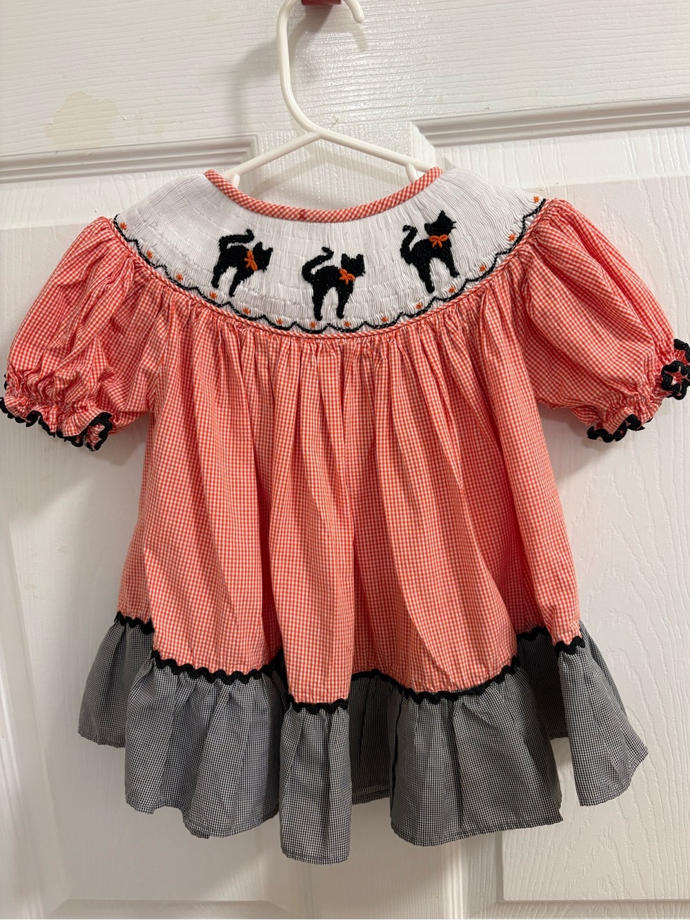 Barefoot orange gingham toddler dress featuring white smocking at the neckline